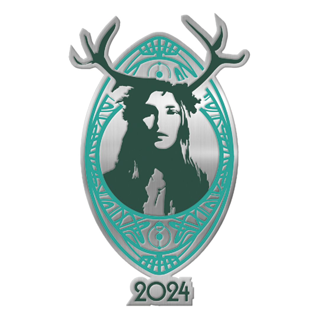 The Isle of Wight Pin Badge by The Isle Of Wight Festival Shop features a metallic emblem of a woman’s face with large antlers in an oval frame with silver and teal details, intricate patterns, and “2024” beneath the design.